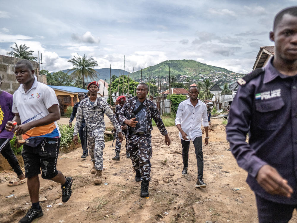 A combined military and police task force, including some in plain clothes, return to their vehicles after arresting a suspected kush dealer in Waterloo, Sierra Leone.