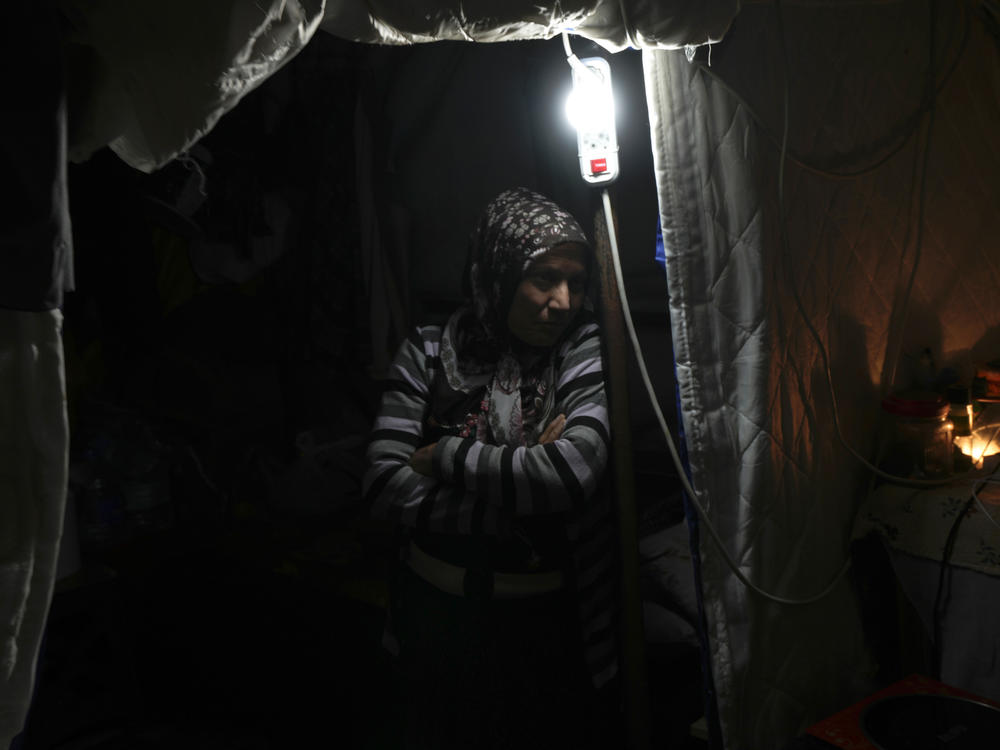 A woman stands next to a lamp inside a tent in Antakya, southern Turkey, on Jan. 12.