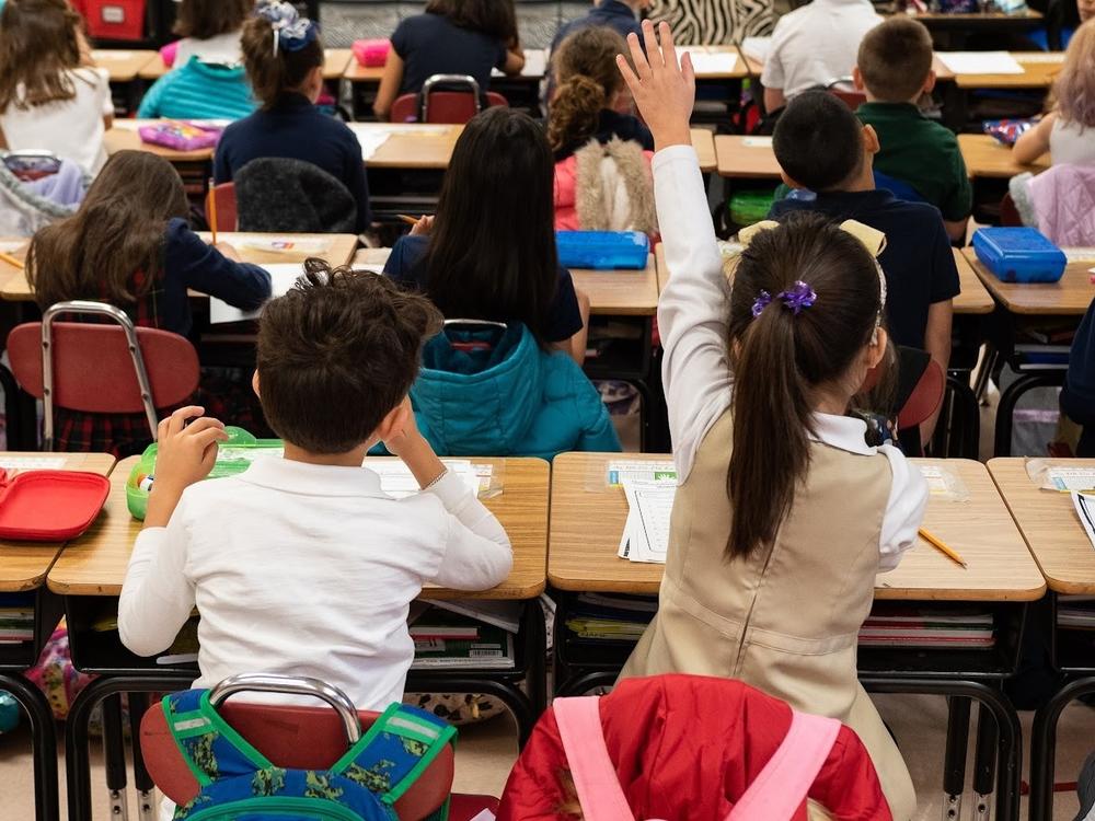 A second grader raises her hand in class at Nichols Hills Elementary School in Oklahoma City in 2020. Under a new bonus program aimed at addressing teacher shortages, over 500 educators received bonuses of up to $50,000.