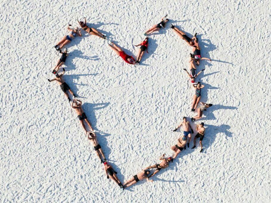 Lovers of winter swimming draw a heart as they pose lying on the icy beach after swimming in the icy water of the Baltic Sea in Gdansk, Poland, on Valentine's Day, Feb. 14, 2021.