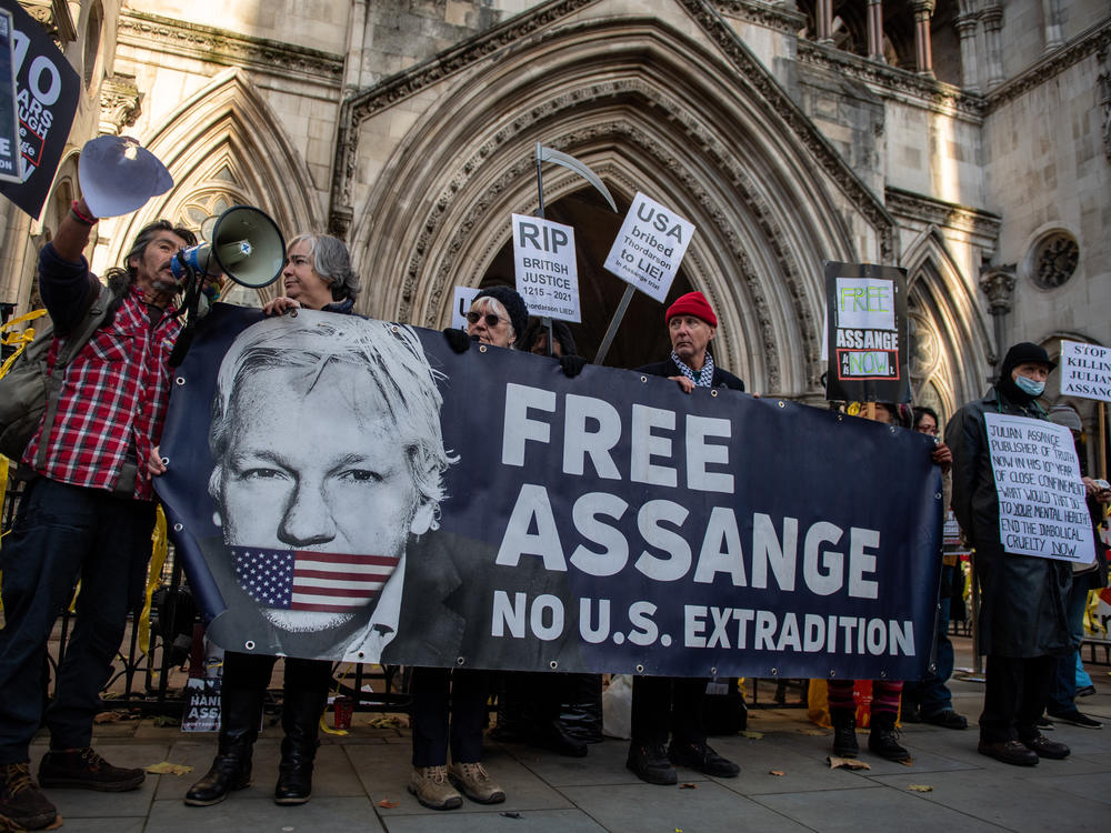 Julian Assange supporters hold up a banner that says 