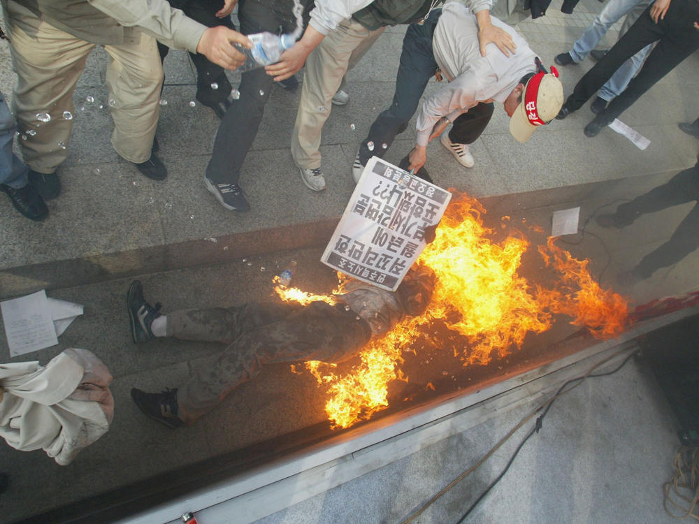 South Koreans help a protester who set himself on fire during a rally on May 7, 2004, in Seoul. A taxi driver attempted suicide during a rally demanding improvement of labor conditions and higher salaries for taxi drivers. The driver survived the attempt.