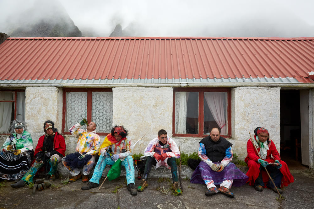 A group of Okalolies — Calvin Green (from left), Dean Repetto, Christopher Swain, Shane Green, Kieran Glass, Cedric Swain and Callum Green — take a break from roaming around the village. Roaming normally lasts a few hours, and the men will stop for breaks at friendly houses to cool off before putting their masks back on.
