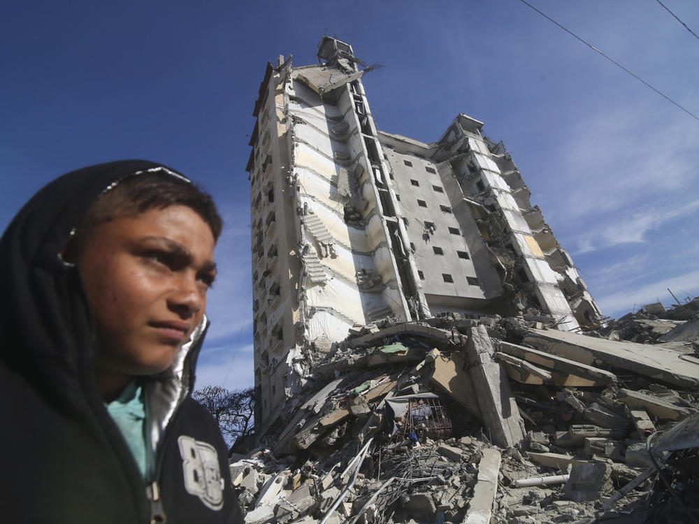 Palestinians walk by a residential building destroyed in an Israeli strike in Rafah, Gaza Strip, on March 9.