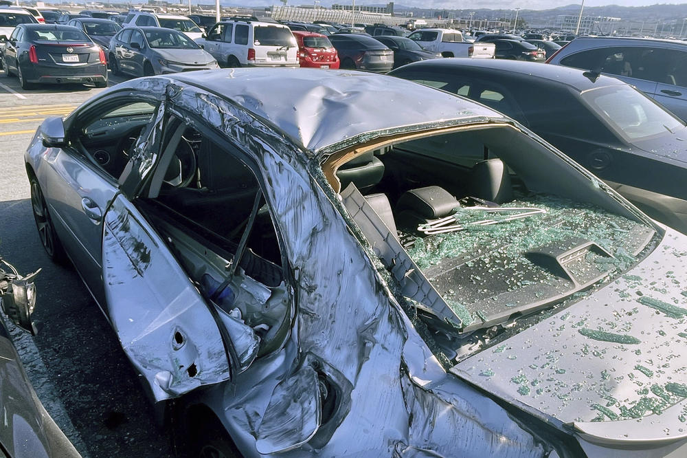 A damaged car is seen in an airport employee parking lot after tire debris from a Boeing 777 landed on it at San Francisco International Airport on Thursday.