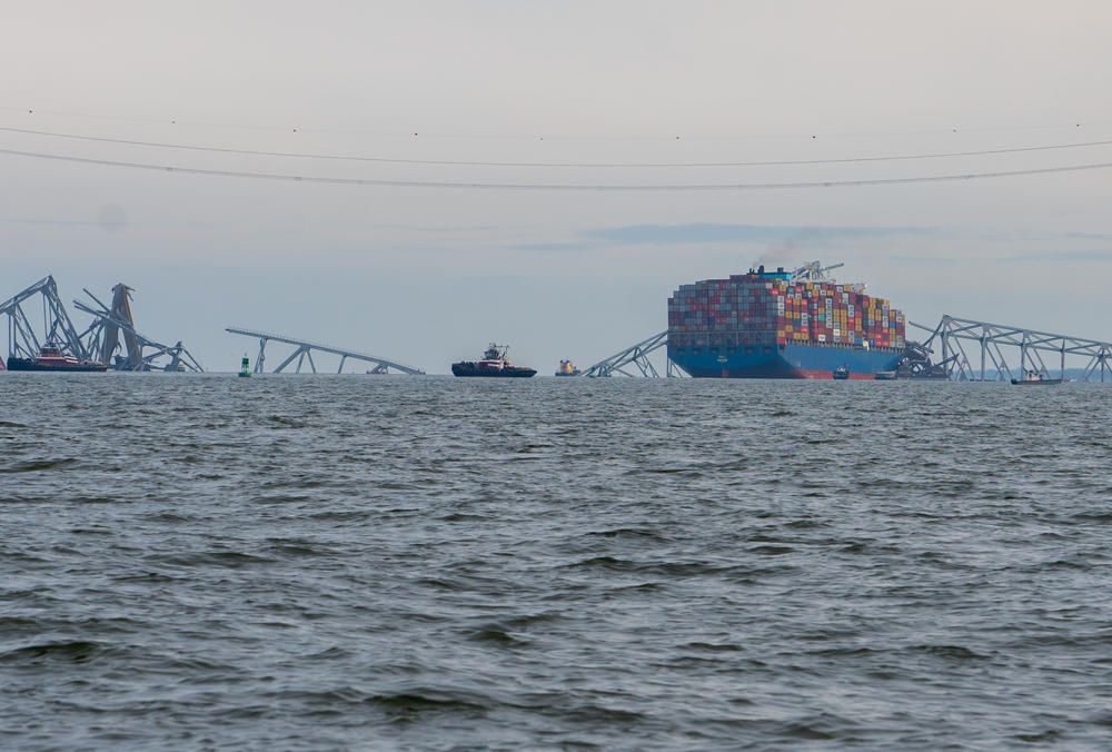 The twisted metal of the Francis Scott Key Bridge hangs over the container ship Dali, which caused the bridge's collapse on Tuesday after striking one of the bridge's piers. The wreckage is blocking the Port of Baltimore's shipping channel.