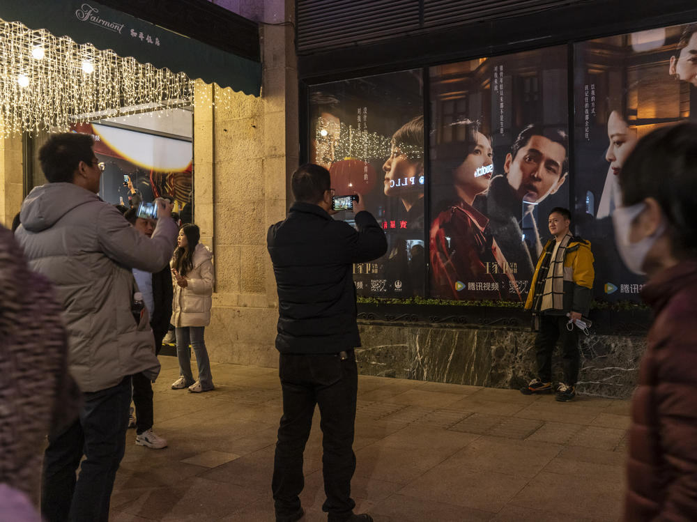 Visitors take photographs in front of posters of the TV show Blossoms Shanghai at the Peace Hotel, in Shanghai, China, on Friday, Jan. 12, 2024. Director Wong Kar-wai's First TV Series 'Blossoms Shanghai' evokes memories of a more open and optimistic period in China.