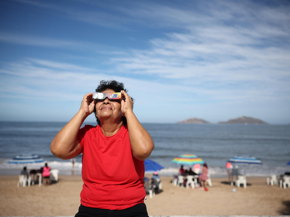 A woman puts on special glasses to see the eclipse on Monday in Mazatlán, Mexico. Many people have flocked to the seaside area to catch a glimpse of the total solar eclipse.