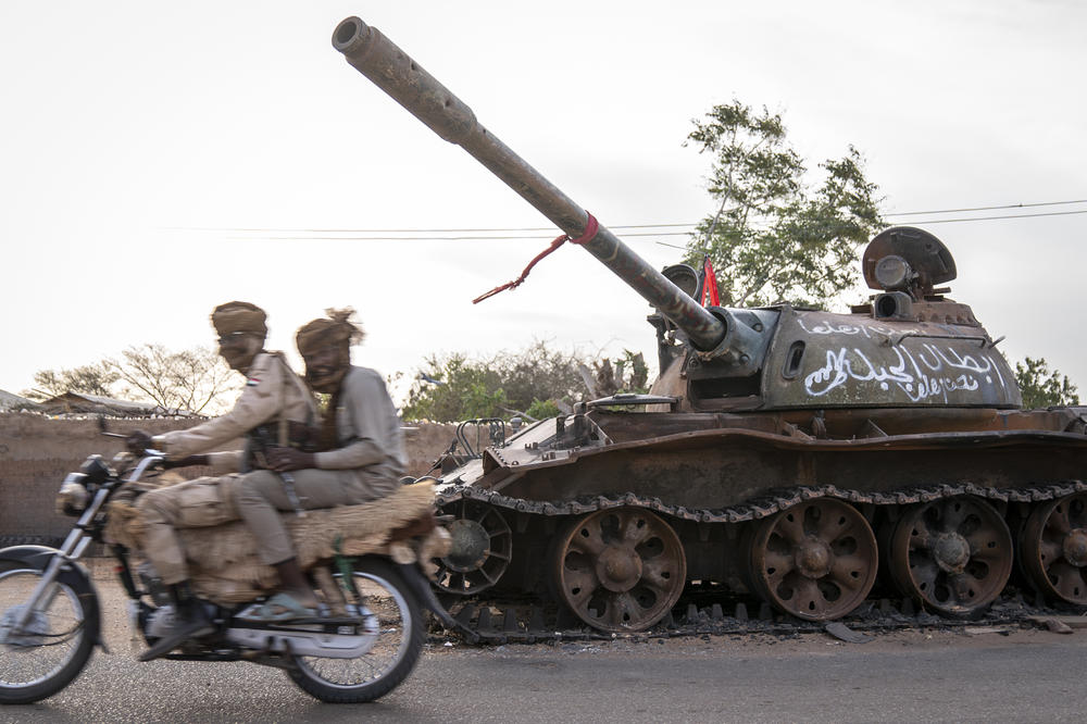 RSF soldiers on a motorbike drive by a destroyed tank belonging to the defeated Sudanese Armed Forces, on a main street in El Geneina, the capital of West Darfur, Sudan, on Feb. 20.