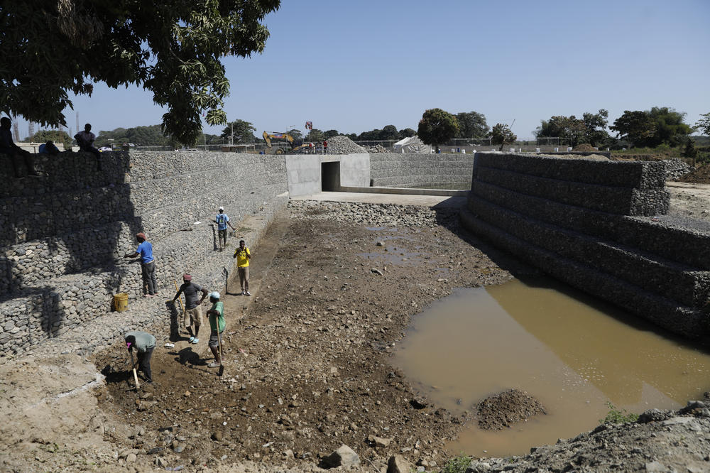 The canal near completion in the border city of Ouanaminthe, Haiti, where construction workers are diligently working to finish the project. Once completed, the nearby farming community will benefit from the canal's water, aiding in the cultivation and yield of their crops.