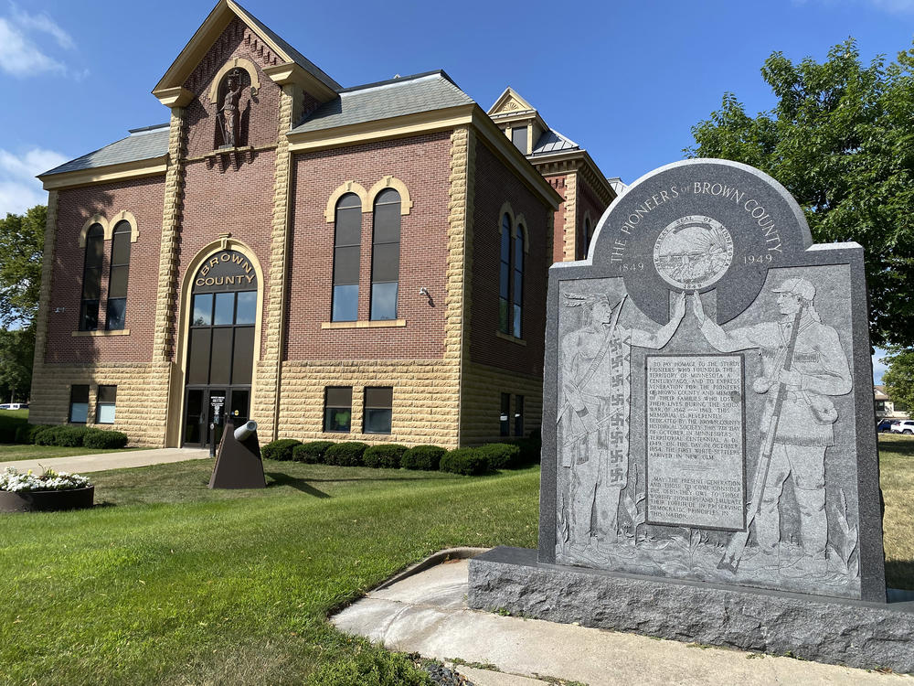 On the New Ulm courthouse lawn, a marker congratulates settlers' founding of the territory of Minnesota. The symbol on the Native person's clothing was an ancient cultural sign for many Dakota tribes.