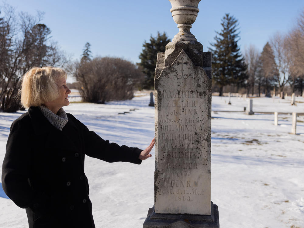 Brown County Historical Society researcher Darla Gebhard touches a grave marker at the New Ulm City Cemetery in New Ulm, Minnesota.