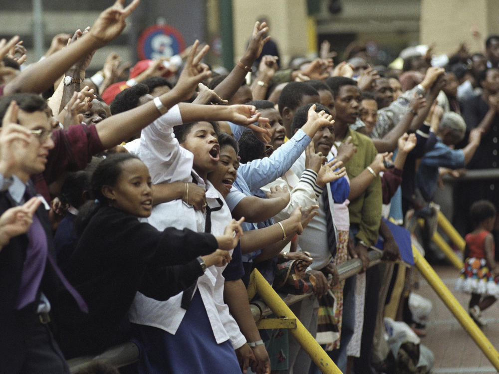 A crowd of people sing and give peace signs during a lunchtime peace march in downtown Johannesburg, South Africa, Jan. 27, 1994 ahead of the country's all race elections.