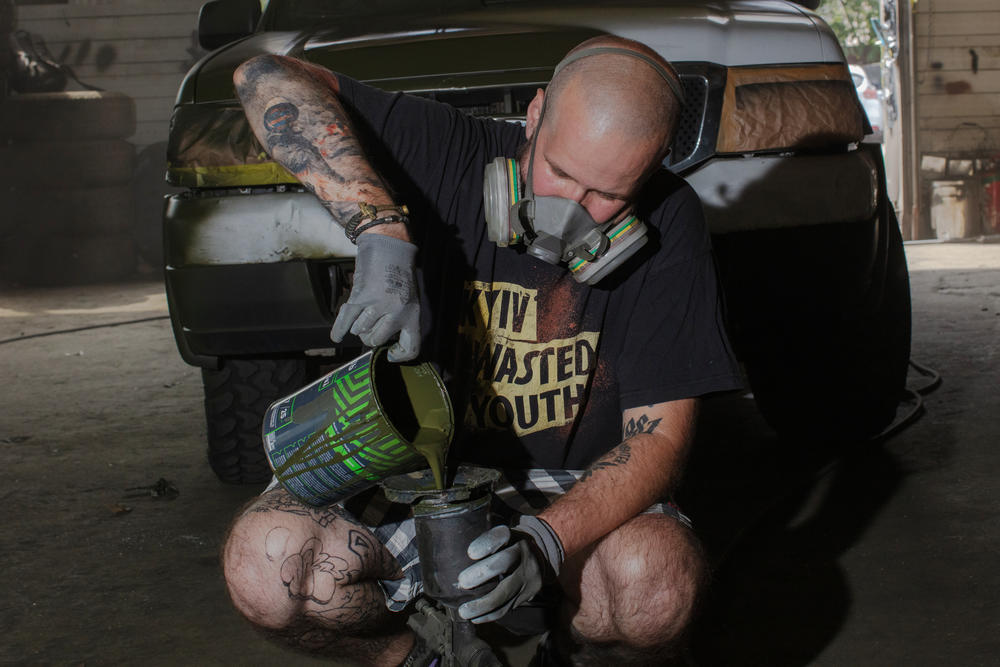 <em>Neak, a 43-year-old Ukrainian graffiti artist, mixes green paint at a workshop in Kyiv, Ukraine. His ETC graffiti crew works to camouflage cars to be sent east to the front line of the war with Russia.</em>