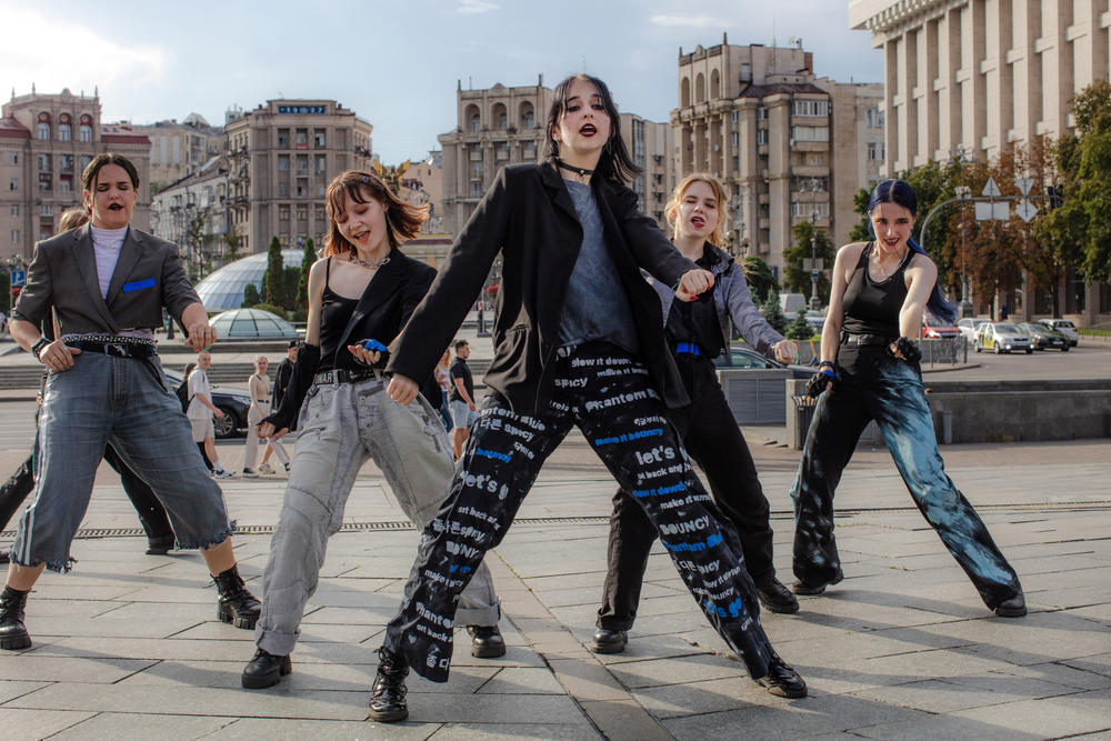 Phantom Blue K-pop cover dance crew performs and records in Maidan Square, surrounded by friends and family who come to support, help with hair and makeup, and cheer them on.