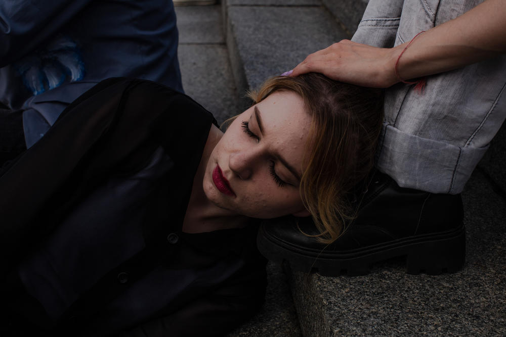 A Phantom Blue dancer rests her head on a friend’s foot on the steps of Maidan Square between recordings.