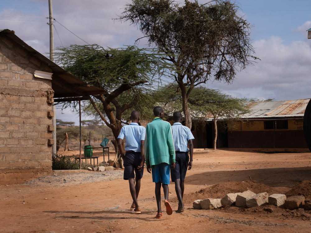 Paris (right) walks to class with fellow morans Saidimu Lolokile (left) and Loshaki Lekiliyo (center). Soon after Paris started at the elementary school, he convinced the others to join him. Now the three boys are inseparable.