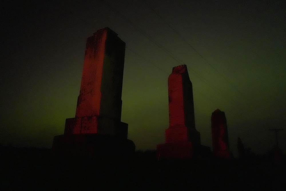 Skidmore, Missouri: Old tombstones stand against the northern lights at a cemetery early Saturday, May 11, 2024.