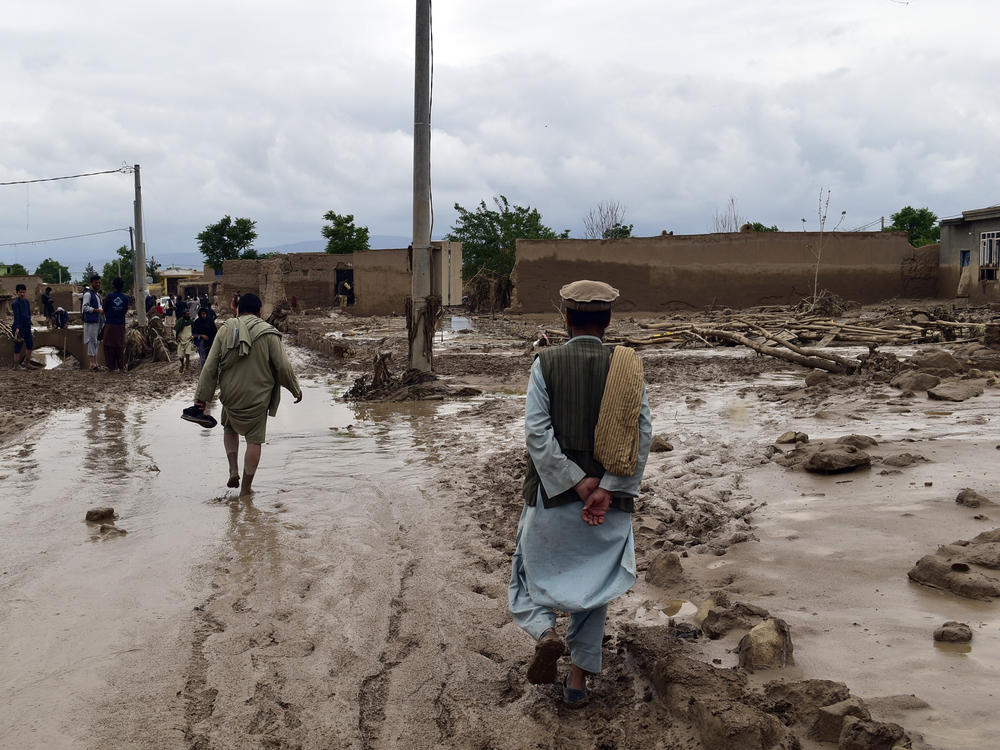 People are seen near to their damaged homes after heavy flooding in Baghlan province in northern Afghanistan on Saturday.