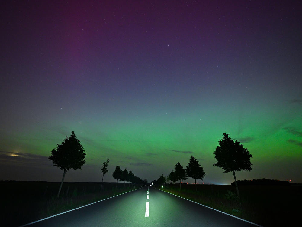 Brandenburg, Germany: Light green and slightly reddish auroras glow in the night sky.