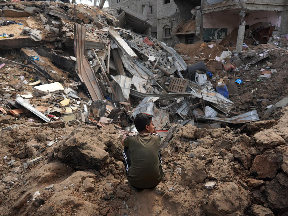 A Palestinian boy sits near the rubble of a residential building destroyed in an Israeli strike in Al-Zawayda in the central Gaza Strip on Saturday.