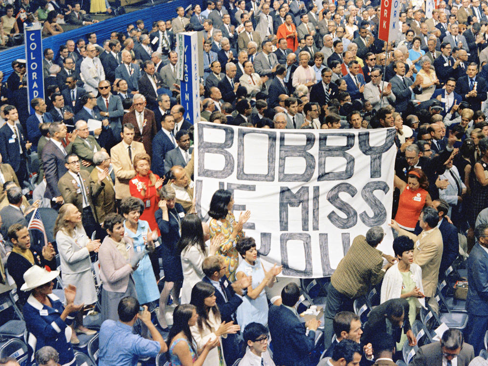 Delegates on the convention floor hold a large banner that reads 