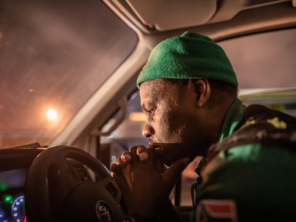 Paramedic Papinki Lebelo waits for a police escort before responding to an emergency call-out in the Red Zone neighborhood of Philippi East in Cape Town, South Africa. Due to a rise in attacks on paramedics, large parts of the city are only accessible to ambulance crews when they have a police escort. This severely delays response times.