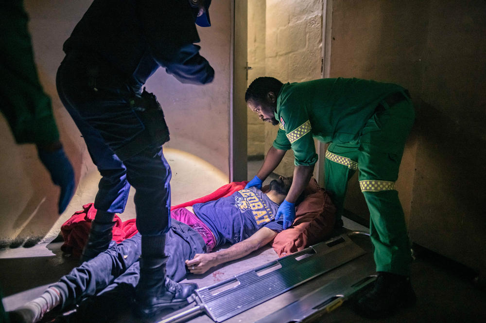 Paramedics prepare to move 35-year-old gunshot victim Ibrahim Ahmed onto a stretcher in his home in the Manenberg neighborhood of Cape Town. Ahmed was shot three times by a hitman from one of Manenberg's many armed gangs. He lay bleeding for an hour before paramedics were able to reach him.