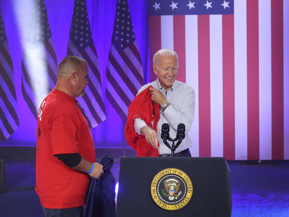 President Biden puts on a United Auto Workers t-shirt in Belvidere, Ill. on Nov. 9, 2023. Biden on Tuesday is announcing new tariffs on imports of Chinese goods, including electric vehicles.