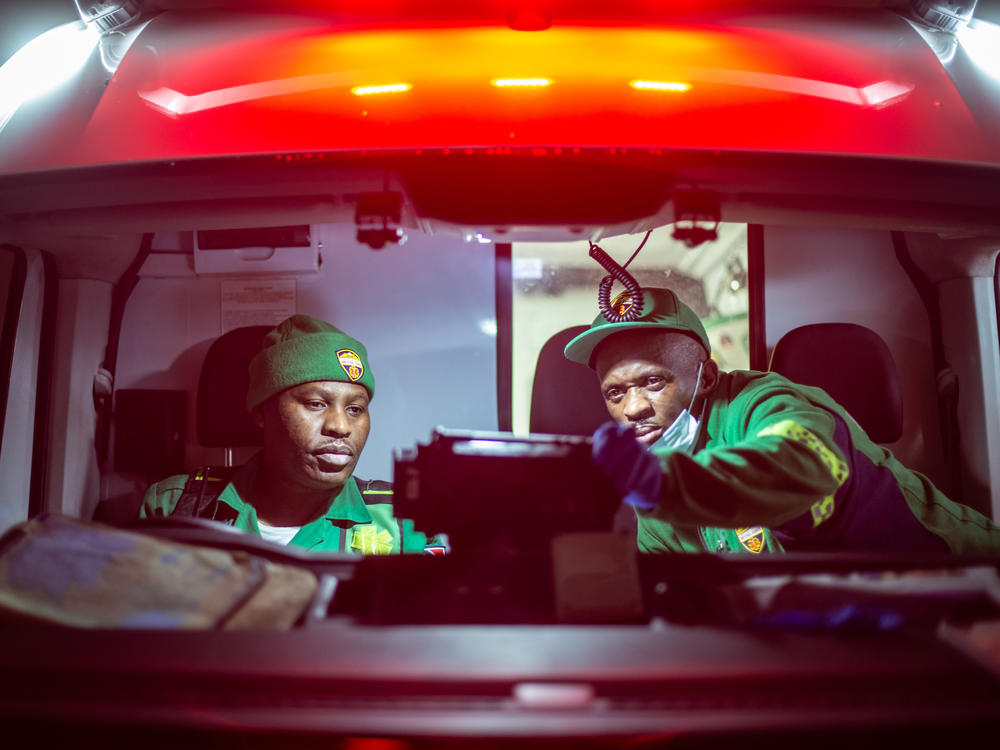 Paramedics Papinki Lebelo (left) and Zuko Faltein look up the details of the next patient they'll be seeing on a screen in their ambulance in Cape Town, South Africa.