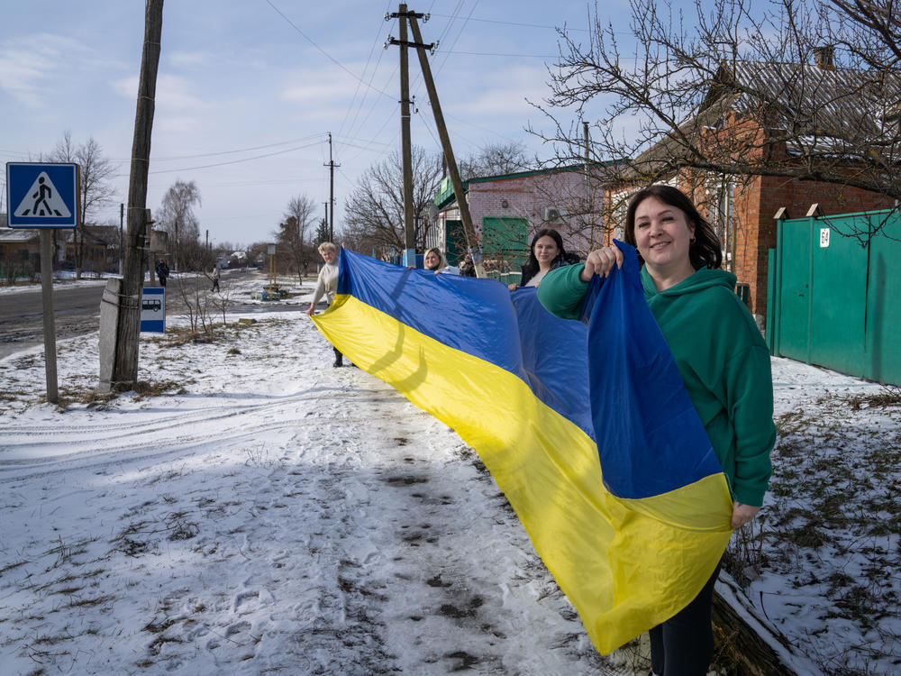 Viktoria Chub (left), Tanya Tymoshenko, Yulia Pavlenko and Natalya Kotsar hold a Ukrainian flag that they use to greet returning POWs as they come from Russian captivity.