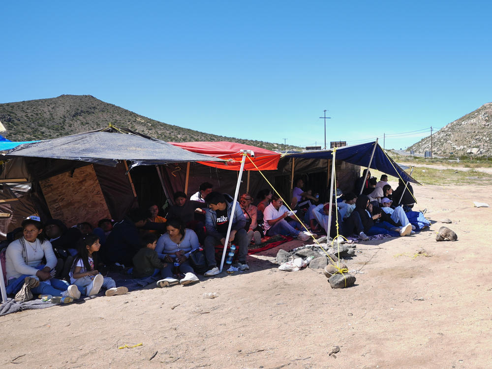 A group of people wait to be processed after crossing the border between Mexico and the United States as they seek asylum in April 2024, near Jacumba, Calif.
