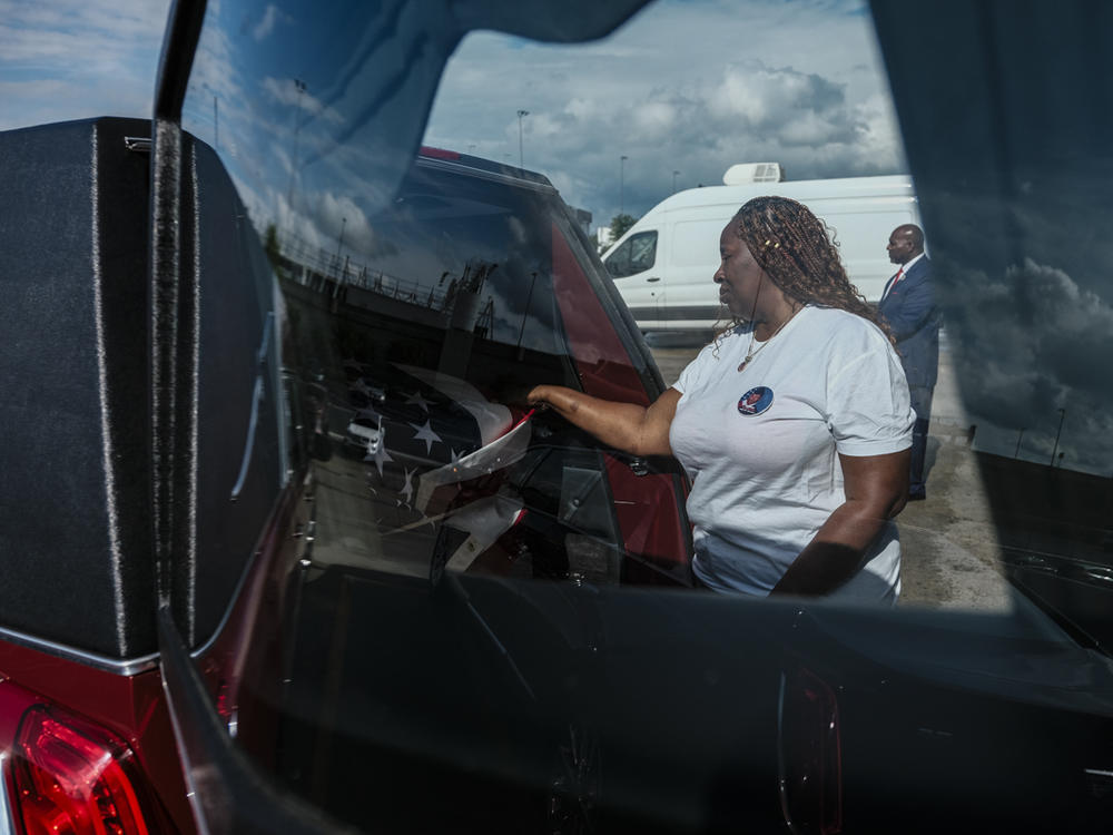 Chantimekki Fortson touches the transfer case of the hearse of her son at the Hartsfield-Jackson Airport in Atlanta on Tuesday.