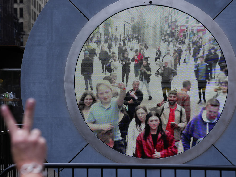 People in both New York and Dublin, Ireland, wave and signal at each other while looking at a livestream view of one another as part of an art installation on the street in New York on Tuesday.