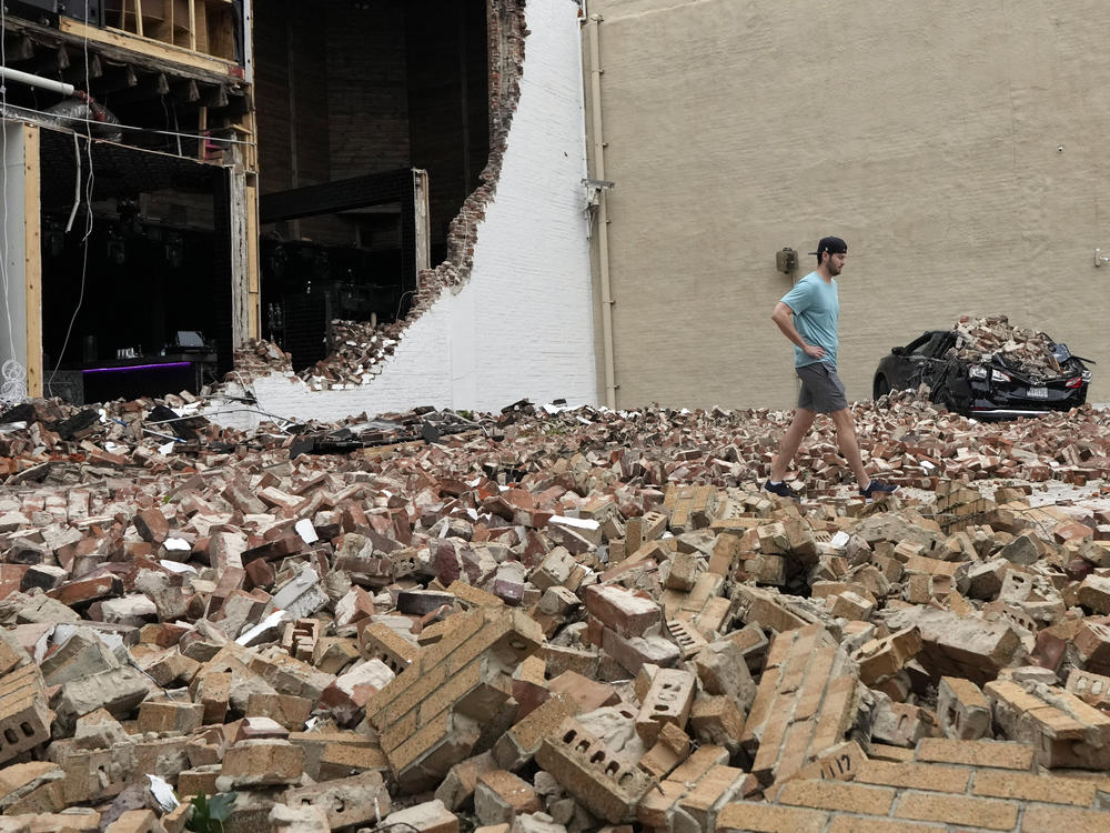 A man walks through fallen bricks from a damaged building in the aftermath of a severe thunderstorm on Friday, in Houston.