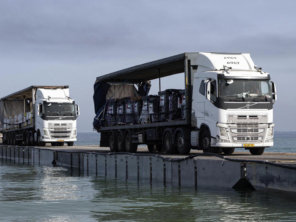 This image provided by the U.S. Army shows trucks loaded with humanitarian aid from the United Arab Emirates and the United States Agency for International Development cross the Trident Pier before arriving on the beach on the Gaza Strip on Friday.