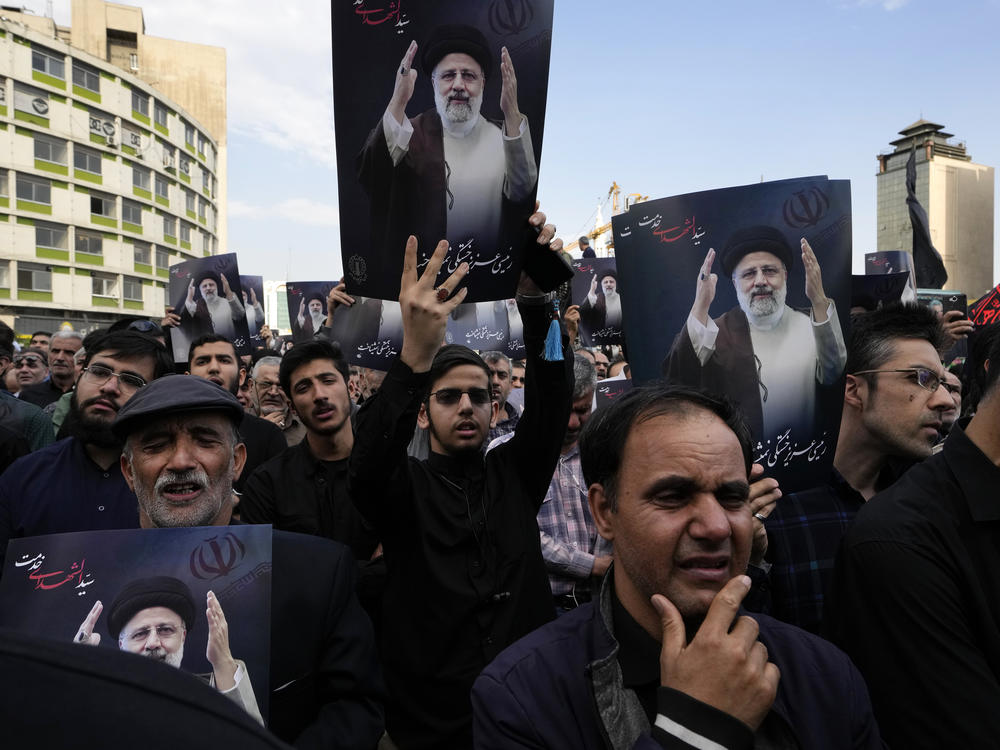 People hold up posters of Iranian President Ebrahim Raisi during a mourning ceremony for him on Monday at Vali-e-Asr square in downtown Tehran, Iran.