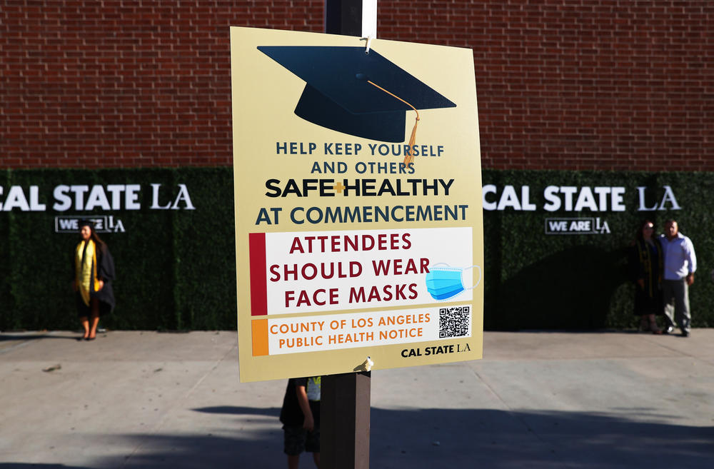 A sign urges the use of face masks for a Cal State Los Angeles commencement ceremony which was held outdoors beneath a tent on campus on July 27, 2021.