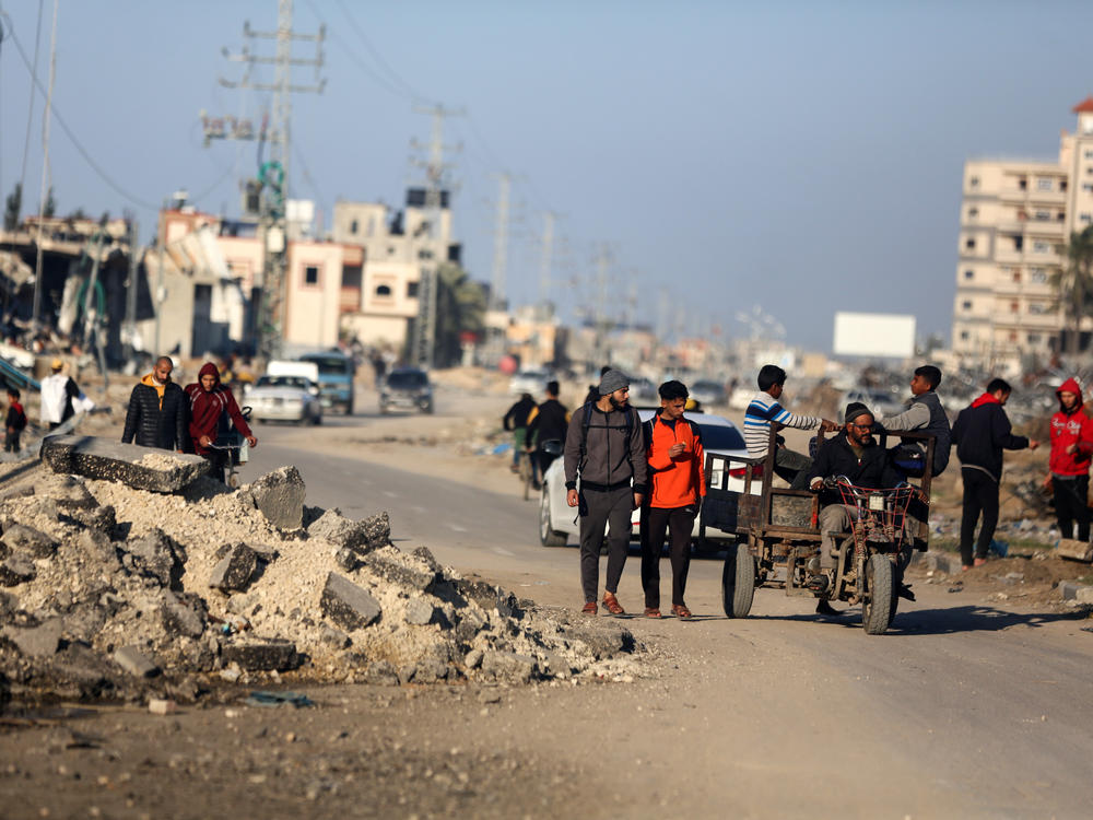 Palestinians walk along Salah al-Din Road in Deir Al-Balah, in the central Gaza Strip.