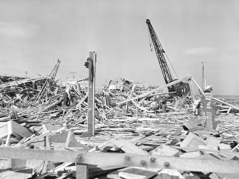 Workmen searched through the debris of what was the carpenter shop on the pier at Port  in Chicago, Calif. on July 18, 1944 after the building was leveled by the explosion of two munition ships the evening of July 17. Other buildings on the waterfront and in the town itself were shattered by the terrific blast, which was felt 50 miles from the scene. 