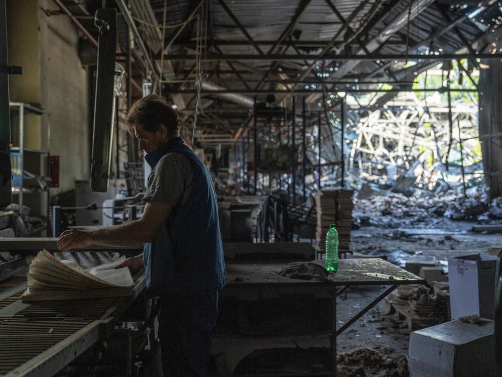 Days after a Russian missile strike hit the Factor Druk printing house, a worker salvages printed sheets of paper while surrounded by the wreckage of a destroyed building, in Kharkiv, Ukraine, on May 27.
