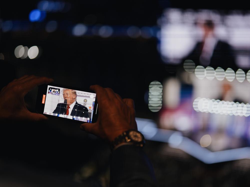 A man records Donald Trump speaking on his phone on the final night of the Republican National Convention. 