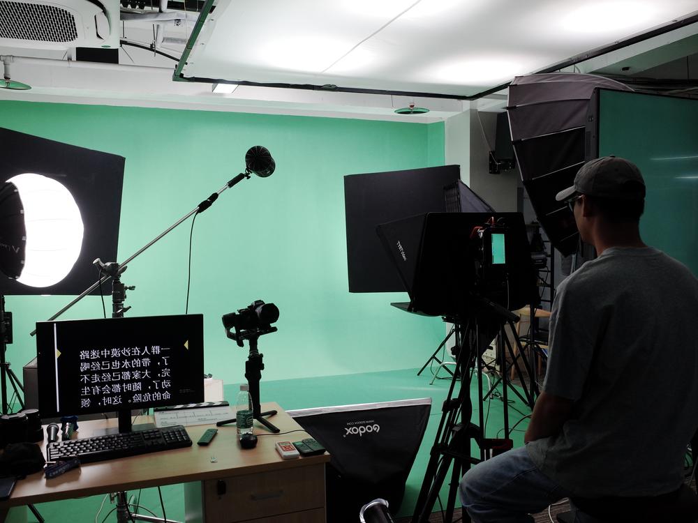At Silicon Intelligence, a technician is preparing to film a person in the studio. The person will read a script and perform specific hand gestures as directed. This footage will be used to create an AI avatar.
