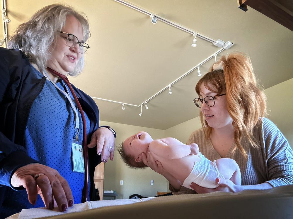 Nurse Barb Ibrahim, left, and Amber Luman, right, weigh the Lumans’ new daughter, Esserley. 