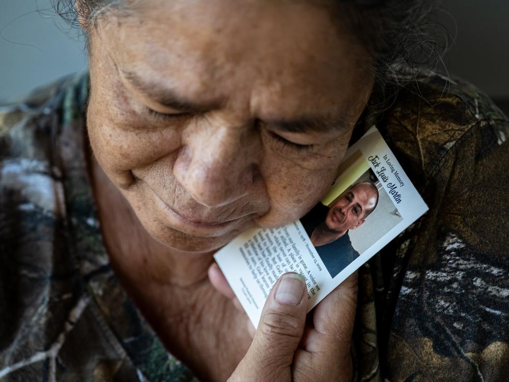 Maria del Carmen Martin, 69, holds a memorial card from the funeral of her late son, Jack Martin, a journeyman plumber who died in a workplace accident in 2019 when a trench that he was laying pipe in collapsed. 