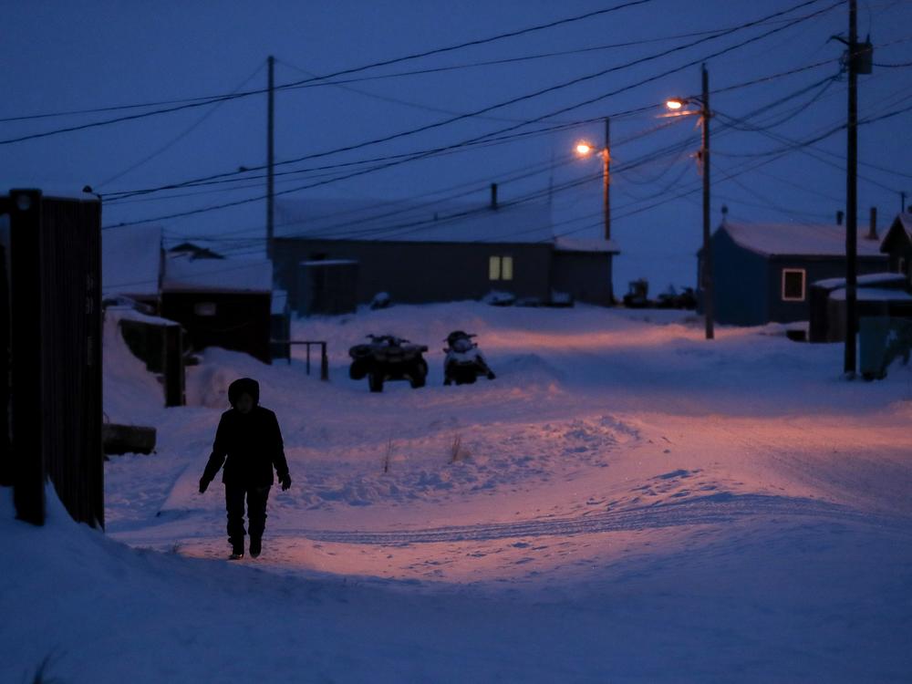A woman walks before dawn in Toksook Bay, Alaska in 2020. Congress approved millions of dollars to connect the community to the new site for the village of Newtok, which was forced to move because of erosion related to climate change. Many scientists who worked on climate-related projects struggled to continue their work under the Trump administration.
