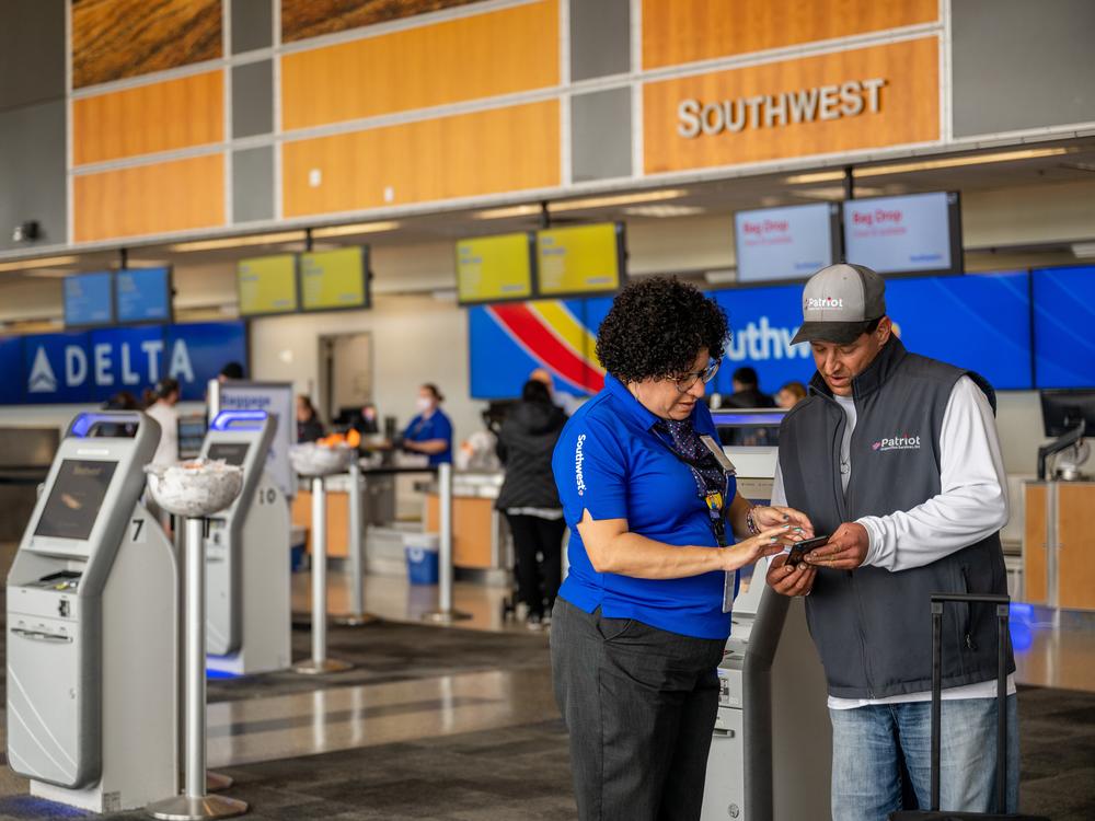 Southwest Airlines unveiled big shifts in how it does business Thursday, saying it will throw out the open-seating model it has used for decades and introduce redeye flights. Here, an employee and passenger are seen at the Austin-Bergstrom International Airport last year in Austin, Texas.