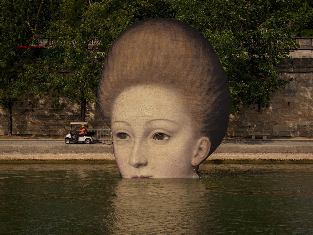 A technician drives in a cart by reproductions of artworks decorating the banks of the River Seine, the day before the opening ceremony of the 2024 Summer Olympics, Thursday in Paris. 