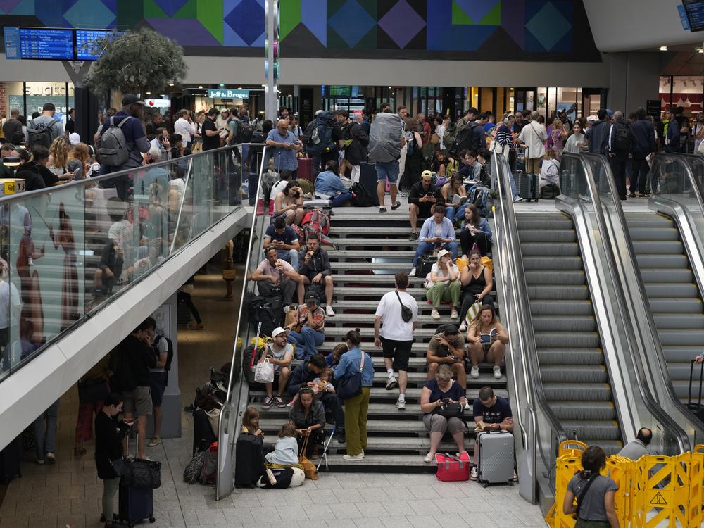 Travelers sit on stairs at the Gare de Montparnasse at the 2024 Summer Olympics on Friday in Paris. Hours away from the opening ceremony of the Olympics, high-speed rail traffic to the French capital was severely disrupted on Friday following what officials described as 
