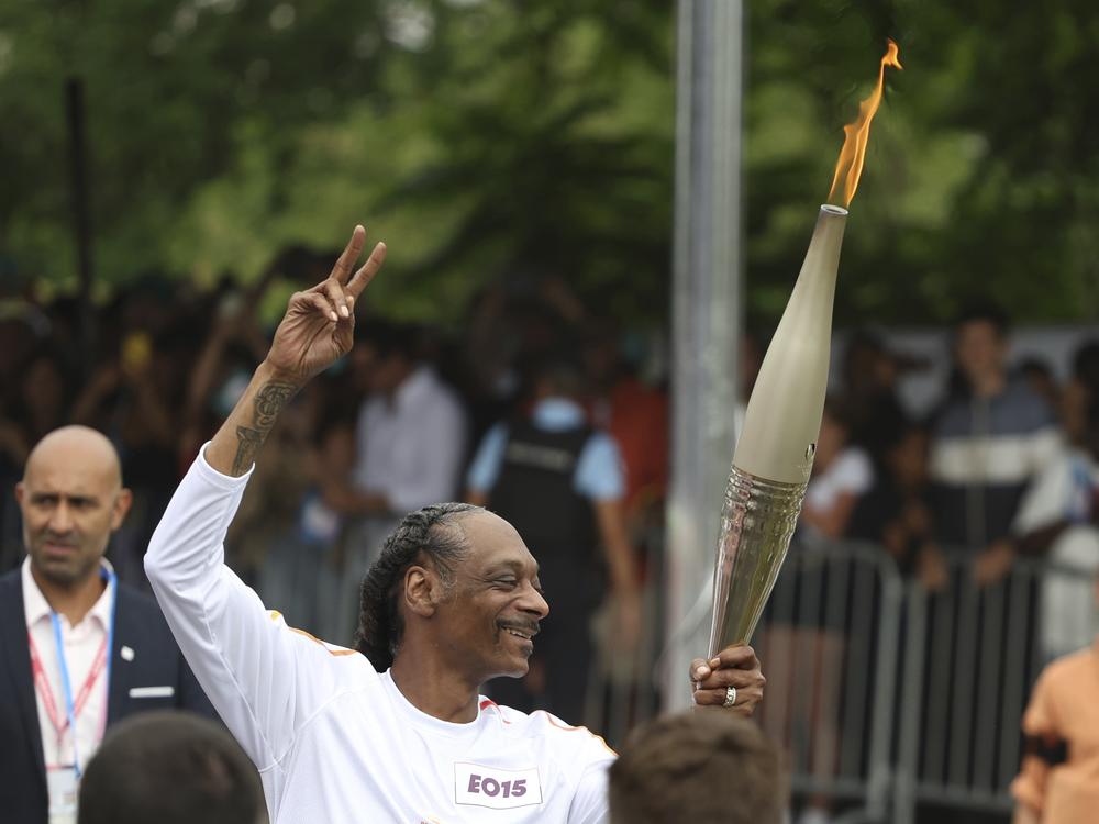 Snoop Dogg carries the Olympic torch at the 2024 Summer Olympics in Saint-Denis, outside Paris.